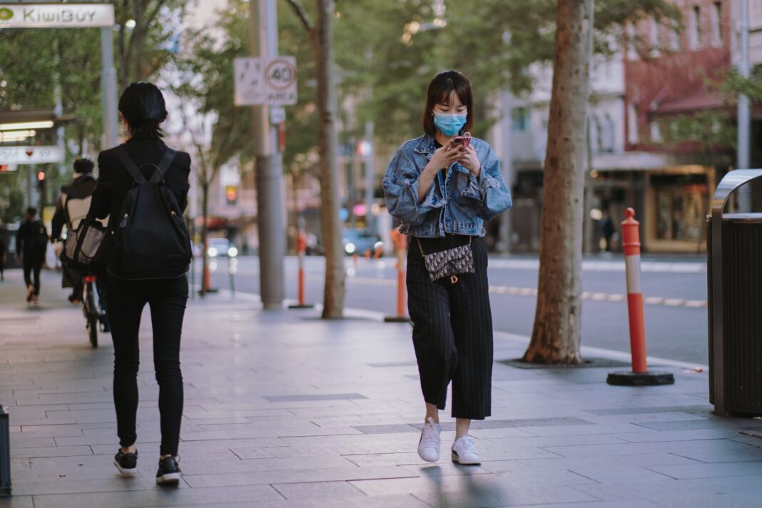 Chica paseando con una mascarilla en el exterior